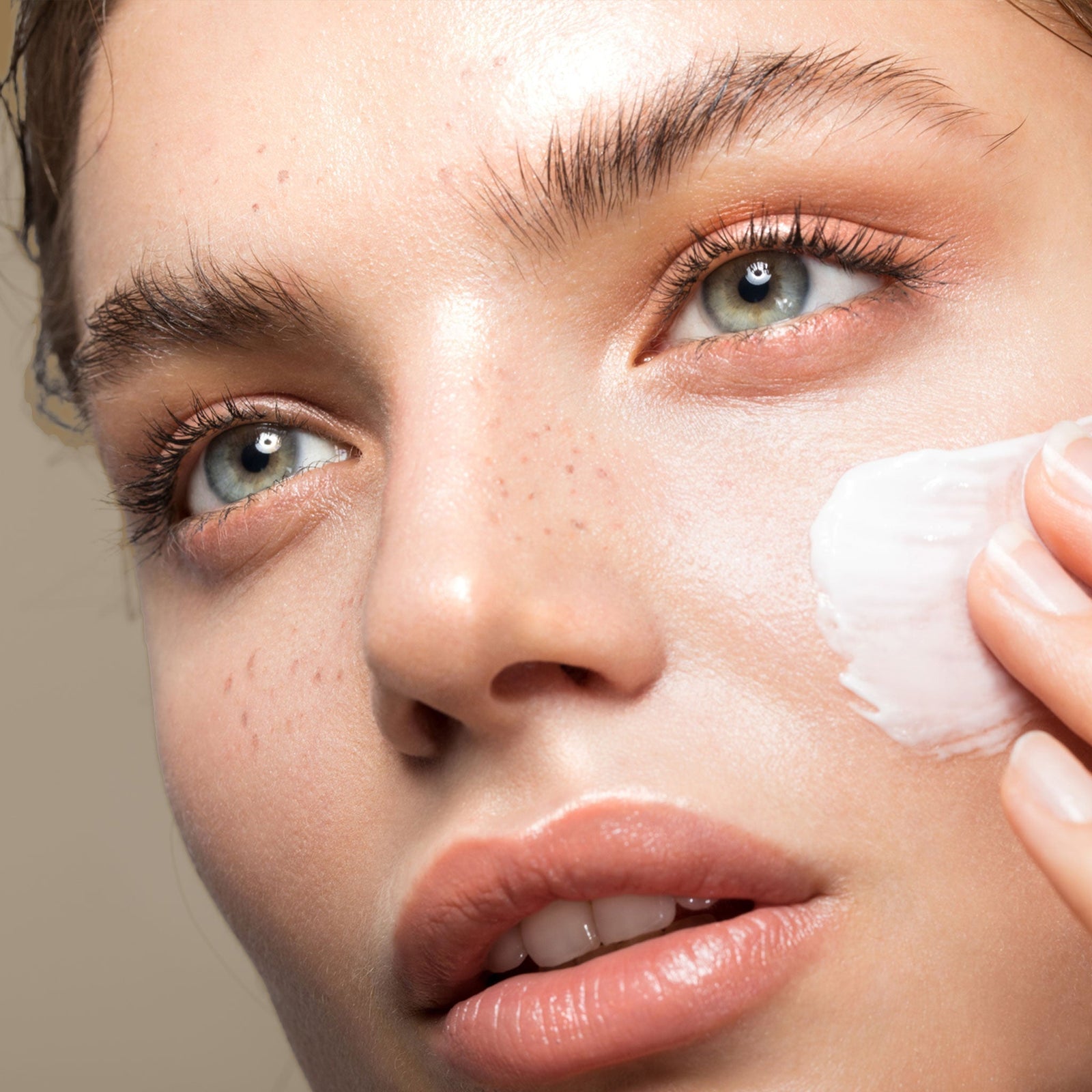 A radiant model applying cream to her face — visually representing the glow-promising benefits of the Exo Face® Perfection Moisturizer Duo Bundle.