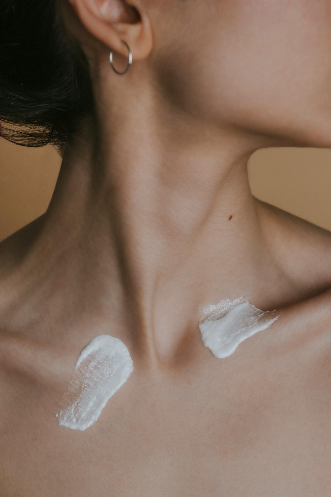 A clean-skinned model displaying two layers of cleanser on the neck — visualizing technique in double cleansing skincare routines.