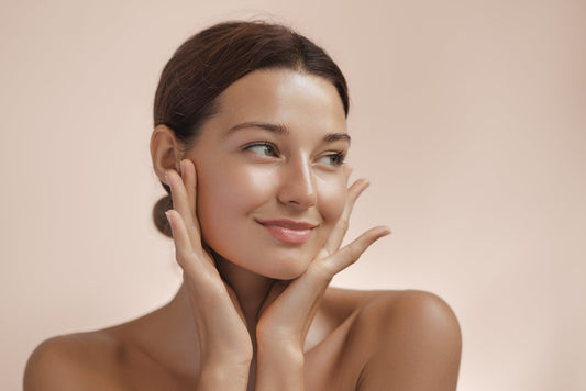 A radiant woman gently touching her face — illustrating the glow and rejuvenation potential of anti-aging exosome skincare.