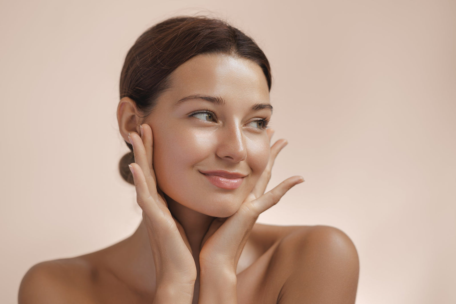 A radiant woman gently touching her face — illustrating the glow and rejuvenation potential of anti-aging exosome skincare.