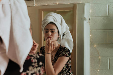 Woman in a morning skincare ritual applying product to her face — illustrating ice-based skincare timing as explored in daily routine features.