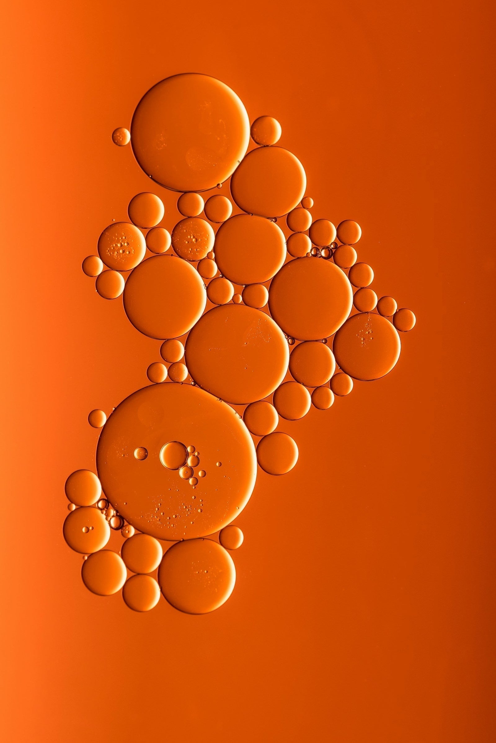 An abstract cellular motif of oil droplets on vibrant orange — symbolizing Exoceuticals®’ advanced exosome technology and the science of targeted skin communication.